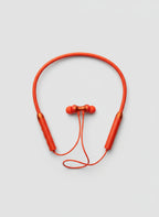 Orange wireless earbuds on a gray textured surface