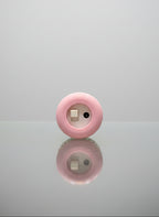 Pink circular object with a reflective surface on a gray background