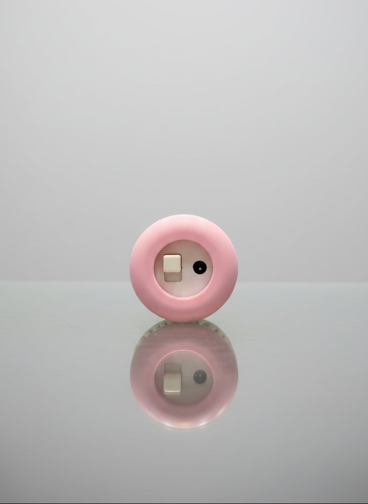 Pink circular object with a reflective surface on a gray background